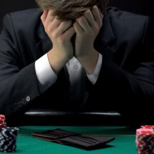 Young devastated businessman losing poker game at casino, gambling addiction