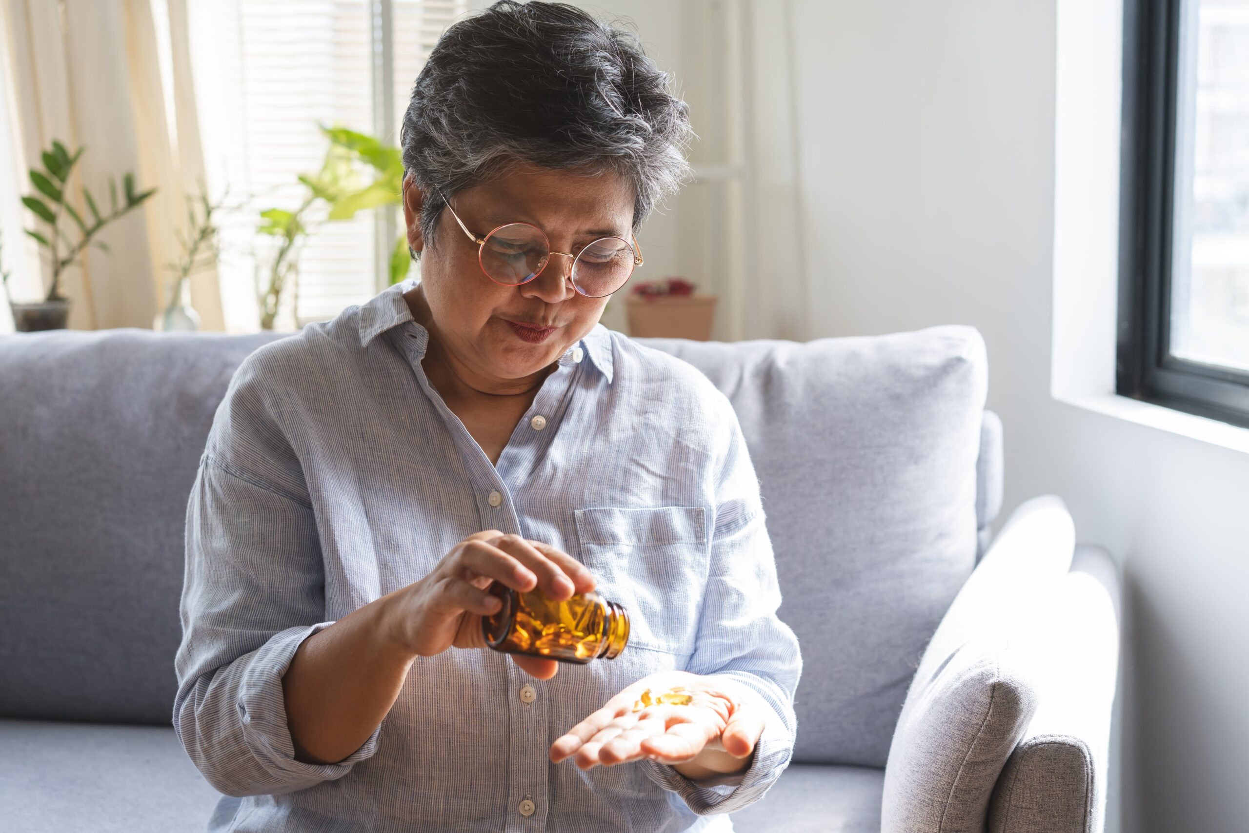 senior holding medication bottles at home Senior adult evaluating prescription medications with concern.
