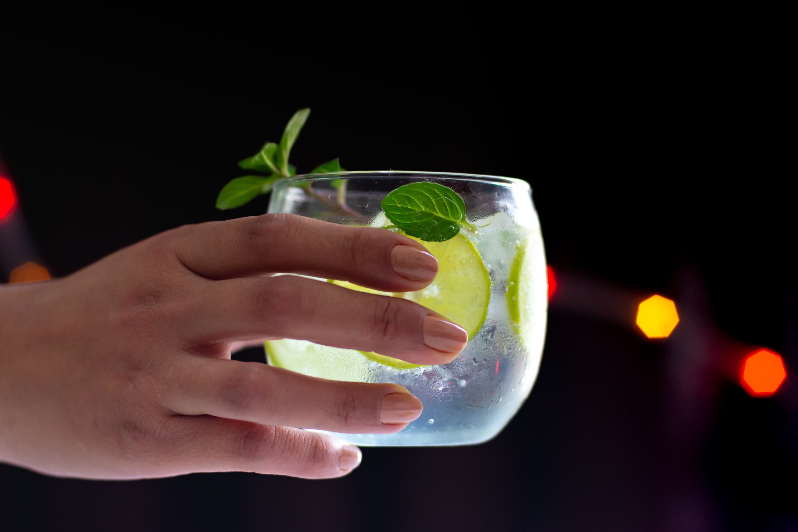 Person holding a non-alcoholic drink confidently, demonstrating how to stay sober in a party culture using a drink prop